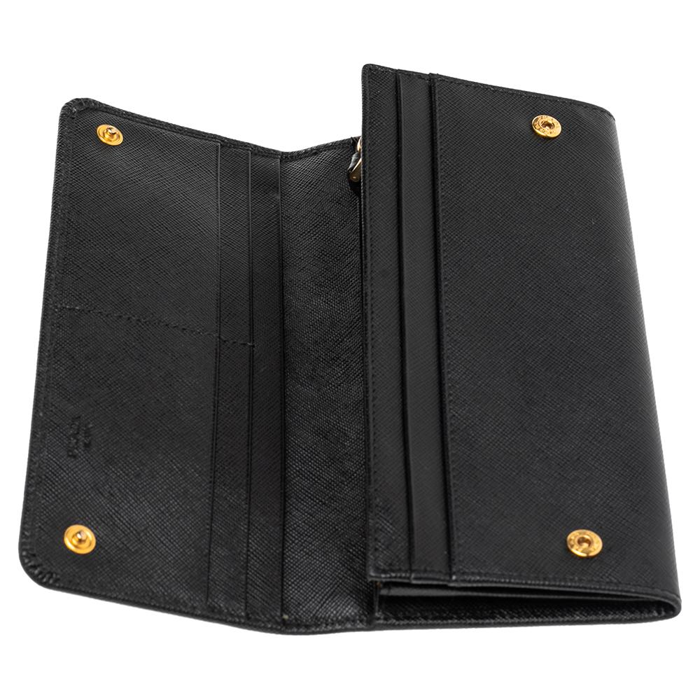 This chic wallet from the House of Prada is fashioned using luxurious black Saffiano leather into a flap silhouette. It comes detailed with a tonal leather bow that has brand lettering. Apart from the interior compartment and inner zip pocket, this