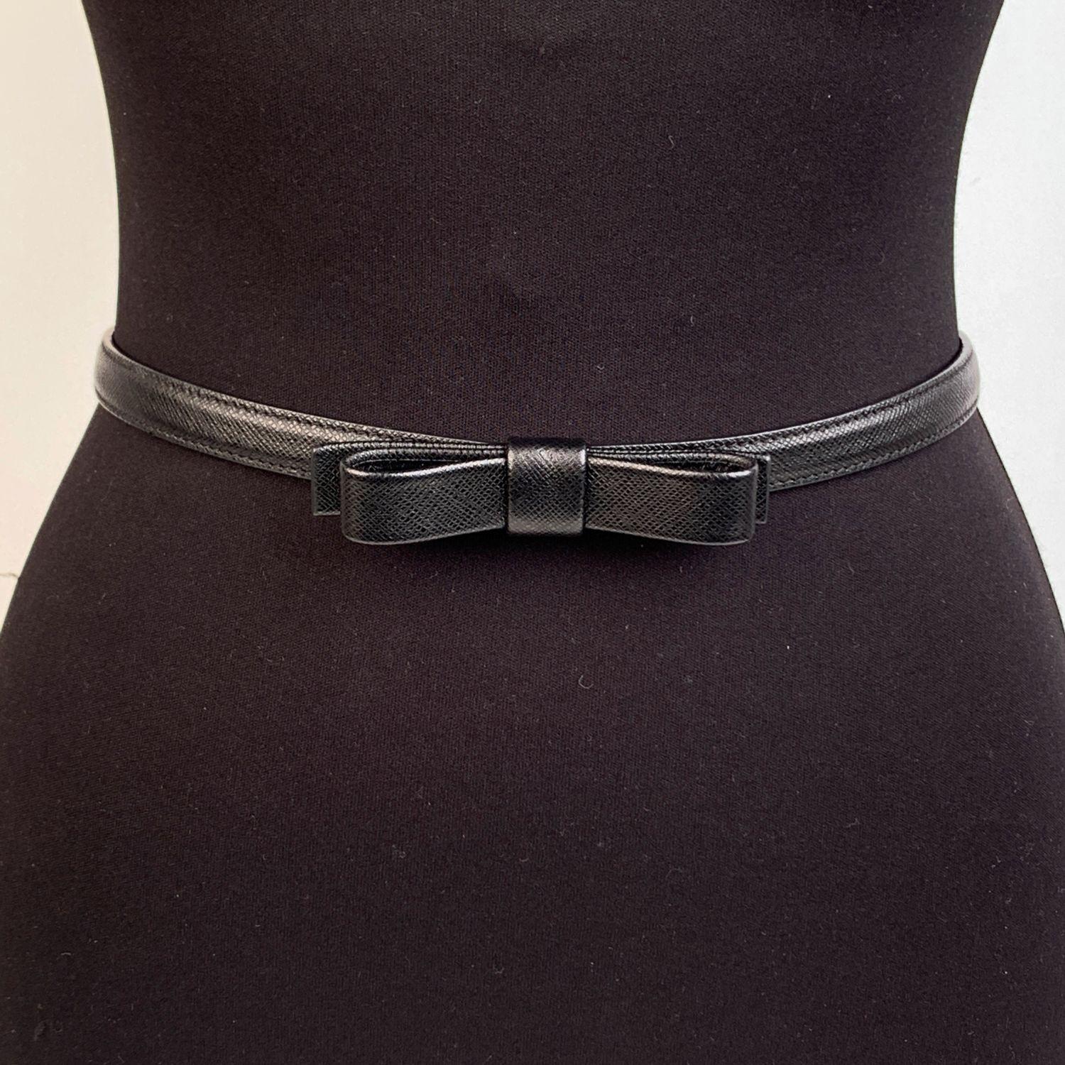 Prada skinny belt, crafted in black Saffiano leather. It features bow detailing on the front. Gold metal square buckle. 'Prada - made in Italy' engraved on the back. 5 holes adjustament. Total length (Buckles included): 37.75 inches - 96 cm. Size