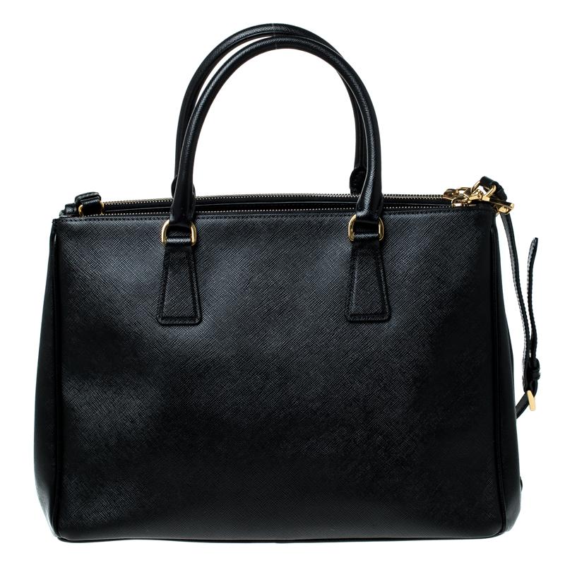 Feminine in shape and grand on design, this Double Zip tote by Prada will be a loved addition to your closet. It has been crafted from Saffiano leather and styled minimally with gold-tone hardware. It comes with two top handles, two zip compartments