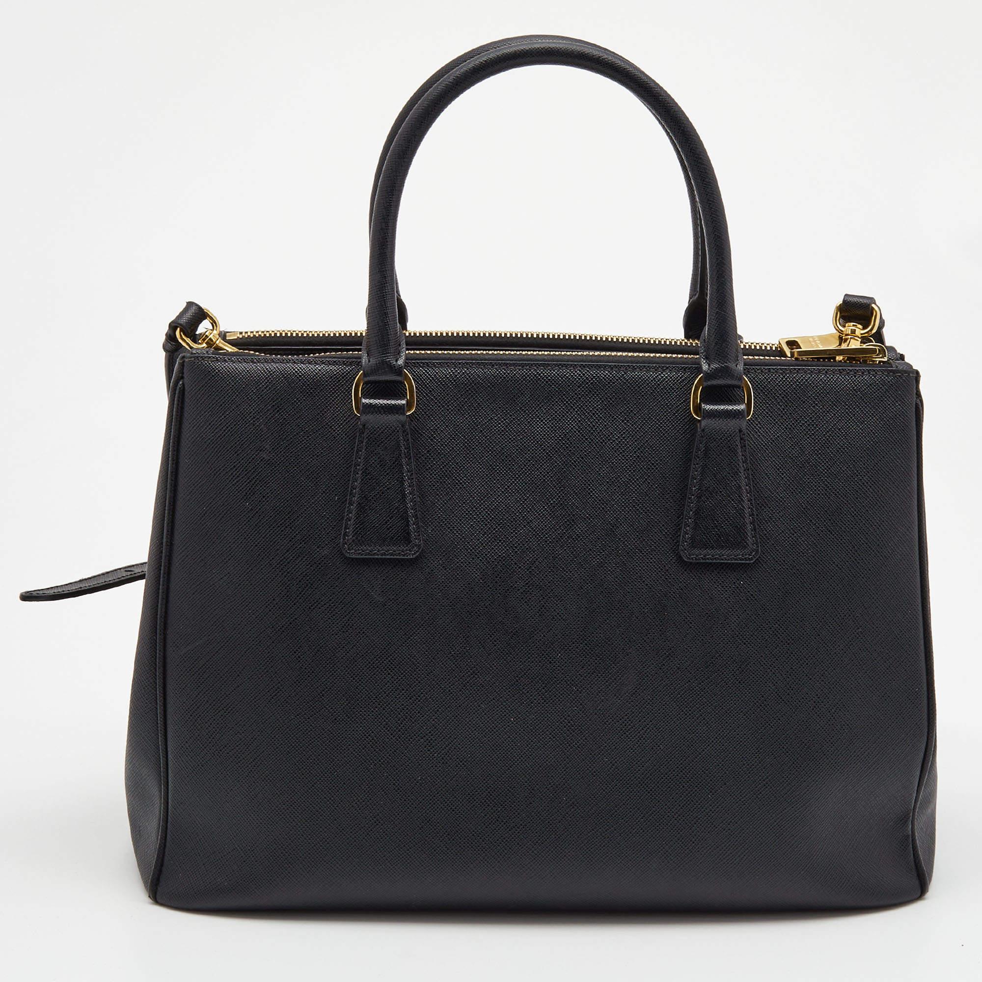 Loved for its classic appeal and functional design, Galleria is one of the most iconic bags from the house of Prada. This beauty in black is crafted from Saffiano leather and is equipped with two top handles, the brand logo at the front, and a