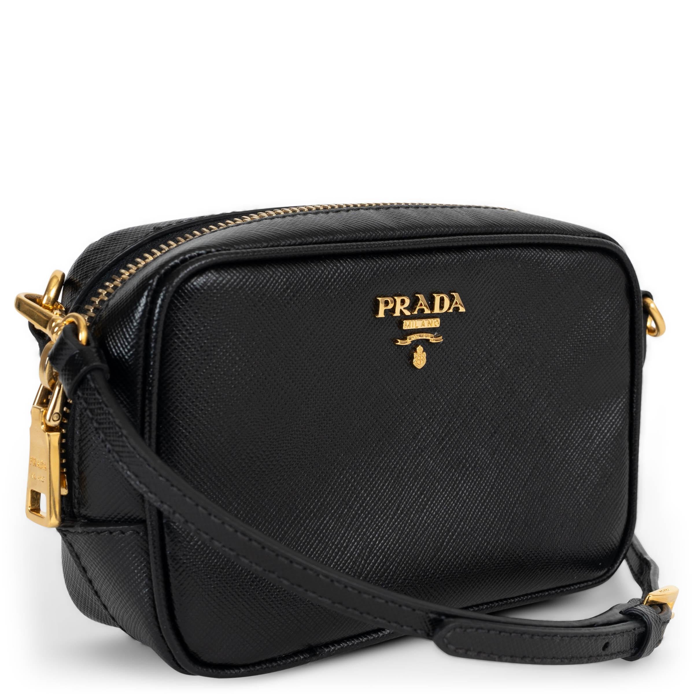 This 100% authentic Prada mini camera crossbody bag is crafted in black Saffiano leather and accented with gold-tone hardware. The front is adorned with Prada’s signature metal logo plaque, while the detachable and adjustable strap offers versatile