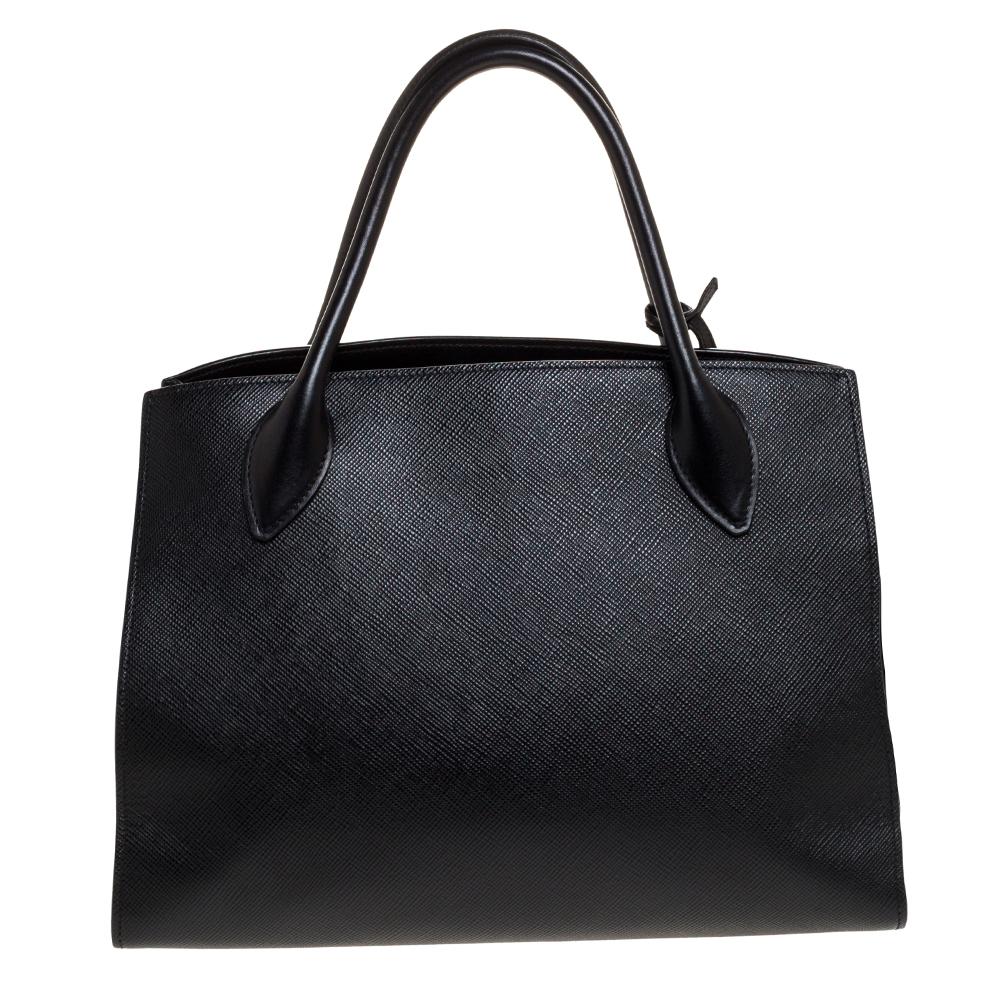 This stylish tote bag by Prada has been crafted to assist you with ease and style on all days. It is crafted from black Saffiano leather. The sleek tote features two handles, a detachable shoulder strap and a spacious interior.

Includes:Original