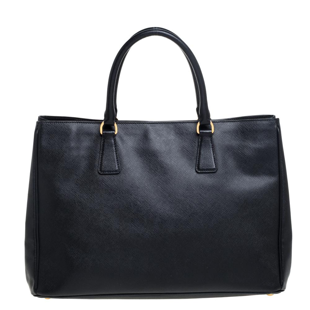 Loved for its classic appeal and functional design, Galleria is one of the most iconic bags from the house of Prada. This beauty in black is crafted from Saffiano leather and equipped with two top handles, the brand logo at the front, and a leather