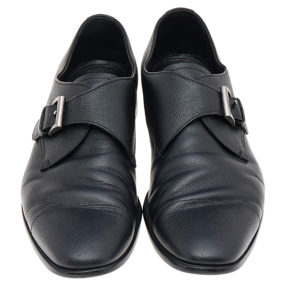 Enhance your formal outfits by wearing these loafers from the House of Prada. They are designed using black Saffiano leather on the exterior with a buckled strap highlighting the vamps. Silver-toned hardware, subtly pointed toes, and a slip-on style