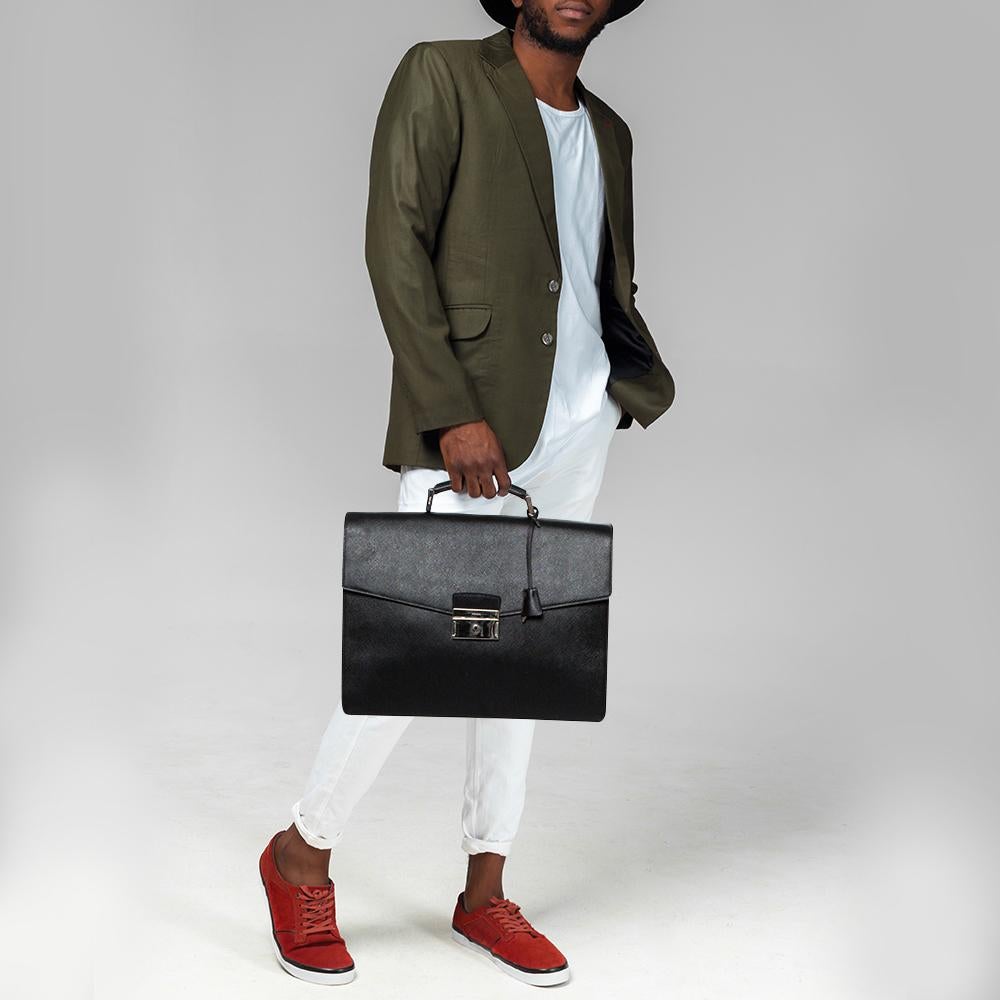 This Prada Double Gusset briefcase brings such a fine shape that you're sure to look fashionable whenever you carry it. The men's briefcase has been crafted from black Saffiano Lux leather and designed with a single handle, a press lock on the flap,