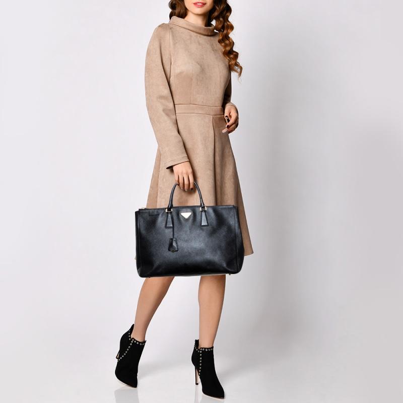 Amado por su atractivo clásico y su diseño funcional, Galleria es uno de los bolsos más icónicos y populares de la casa Prada. Esta belleza en negro está fabricada en piel saffiano y cuenta con dos asas superiores, el logotipo triangular de la marca