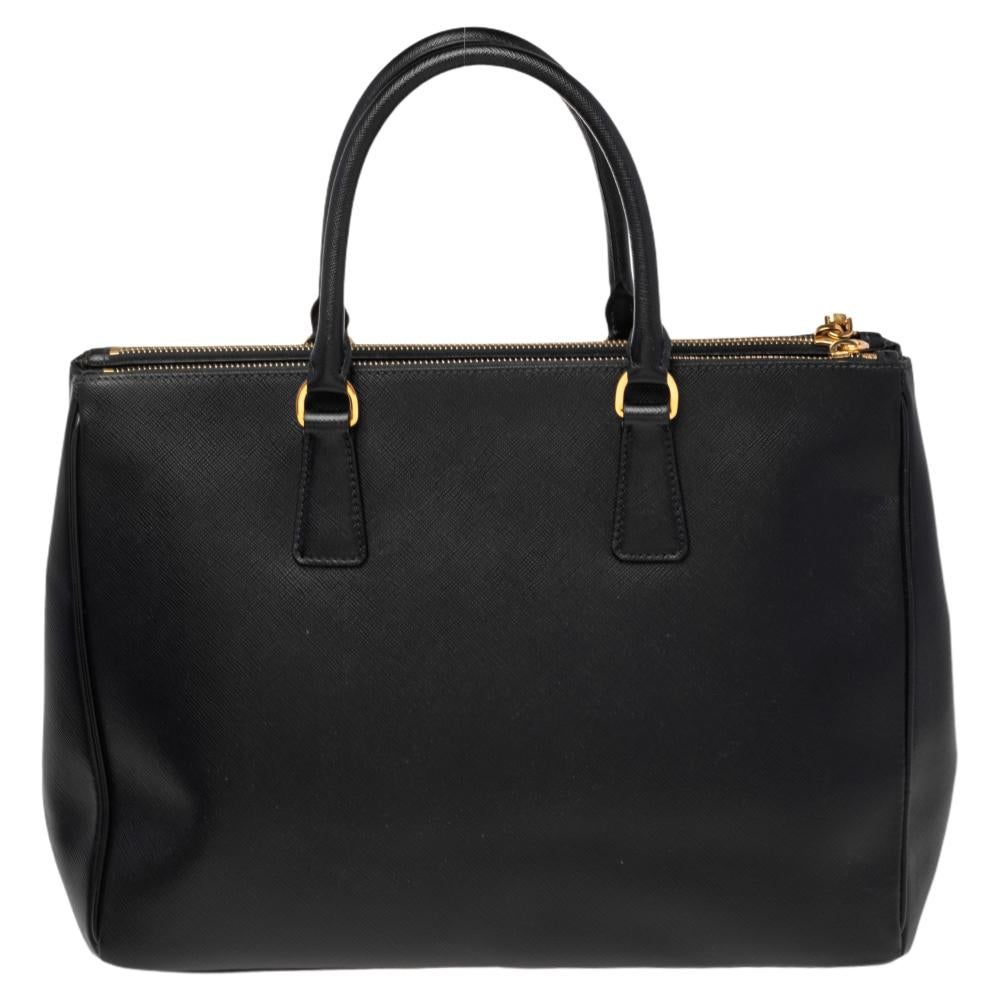 The Galleria tote by Prada carries a functional design that makes a striking statement of its own. The black Saffiano Lux leather exterior and contrasting gold-toned metal fittings lend the bag a very classy appeal. Complete your formal attire with