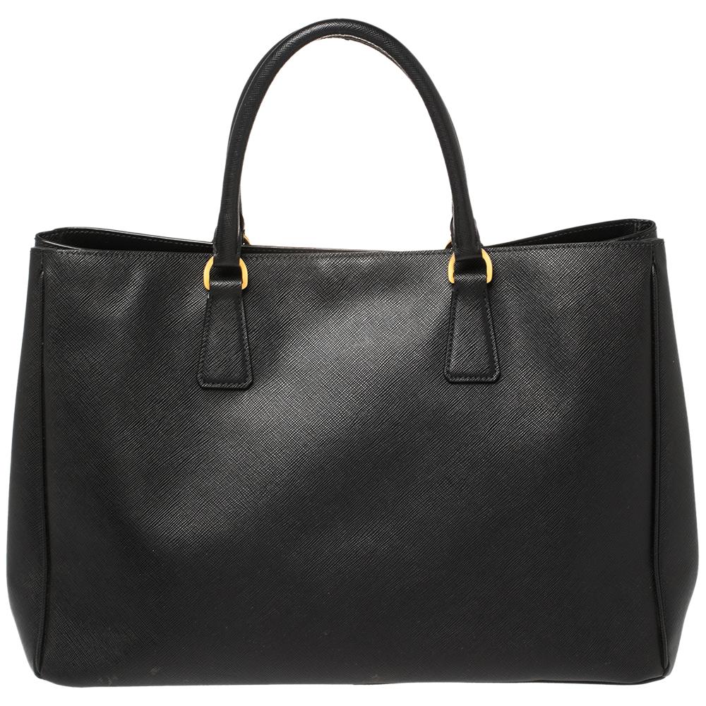 The Gardener's tote by Prada is a wonderful creation. This here is crafted from Saffiano Lux leather and shaped to exude a look of luxury. The bag comes with two handles and a spacious nylon interior for your belongings. Protective metal feet and