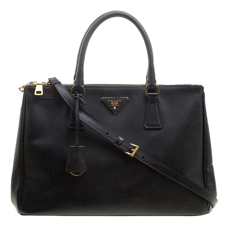 Beautifully crafted from Saffiano Lux leather, this Prada tote is a creation you can't miss. It has a classy black exterior along with two zippers leading to a spacious nylon interior that will hold all your necessities. The bag is held by two