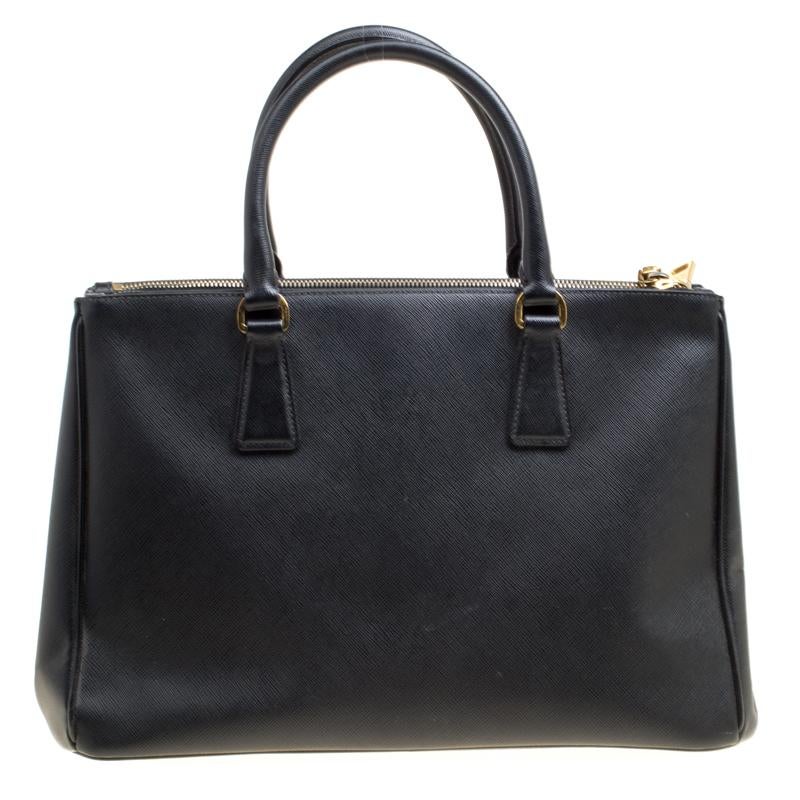 Stunning in appeal and high on style, this Galleria Double Zip bag by Prada will be a valuable addition to your closet. It has been crafted from Saffiano lux leather and styled minimally with gold-tone hardware. It comes with two top handles, a