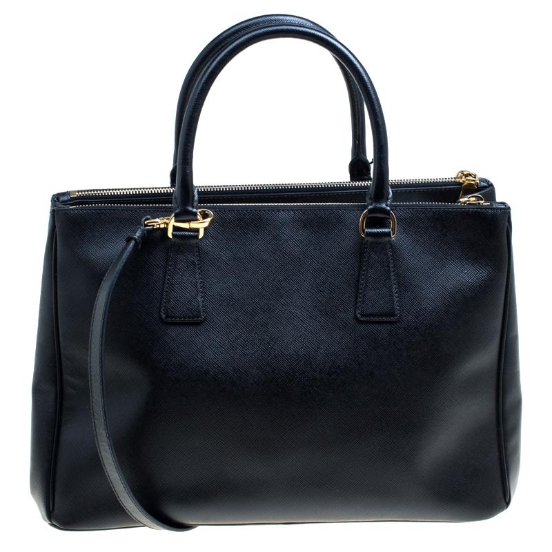 Stunning in appeal and high on style, this Galleria Double Zip bag by Prada will be a valuable addition to your closet. It has been crafted from Saffiano lux leather and styled minimally with gold-tone hardware. It comes with two top handles, a