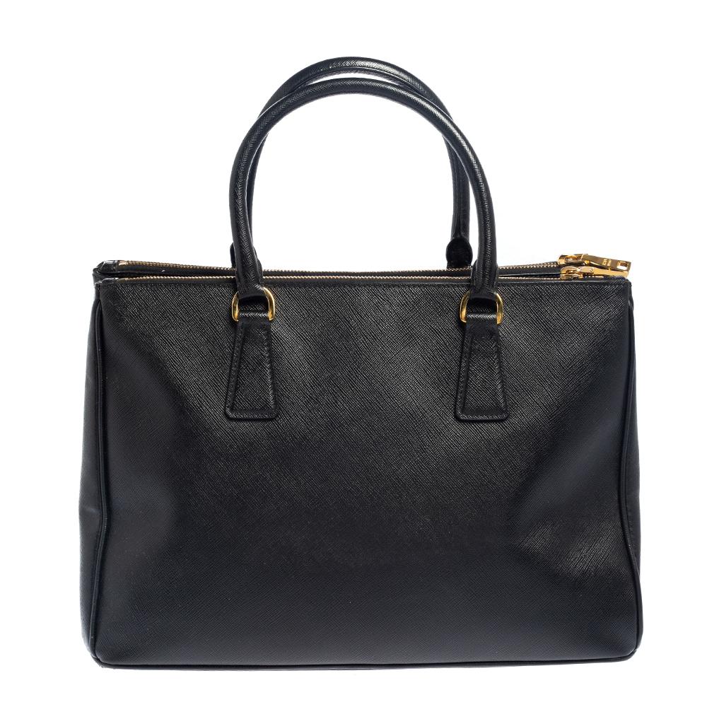 Loved for its classic appeal and functional design, Galleria is one of the most iconic and popular bags from the house of Prada. This beauty in black is crafted from Saffiano leather and is equipped with two top handles, the brand logo at the front,