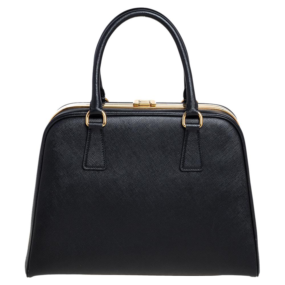 High in appeal and style, this satchel is a Prada creation. It has been crafted from Saffiano leather and shaped to exude class and luxury. The bag is designed with a gold-tone clasp on the top metal frame and comes with two handles and a spacious