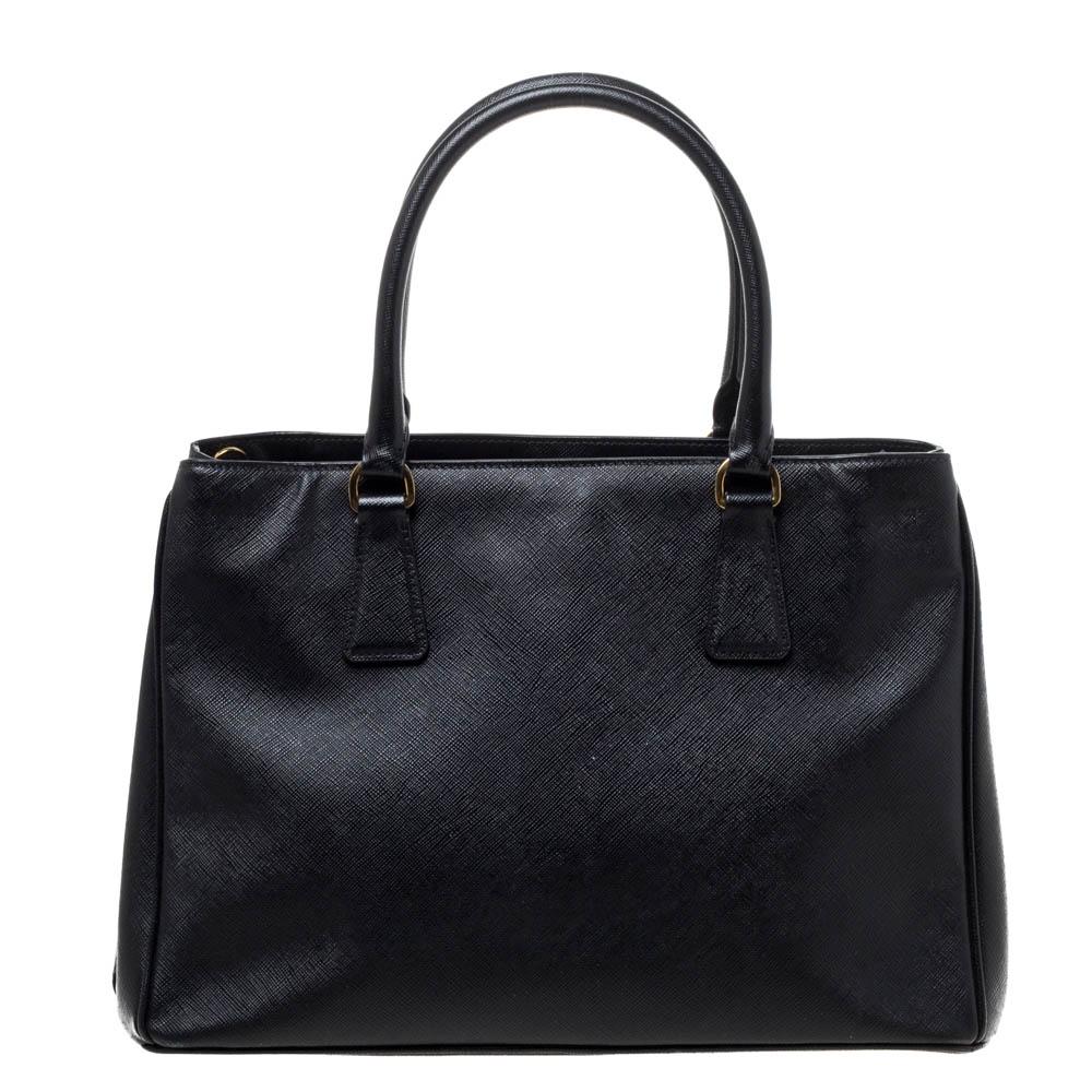 Loved for its classic appeal and functional design, Galleria is one of the most iconic and popular bags from the house of Prada. This beauty in black is crafted from leather and is equipped with two top handles, the brand logo at the front and a