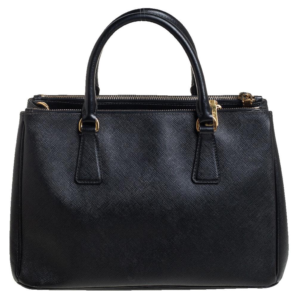 Loved for its classic appeal and functional design, Galleria is one of the most iconic and popular bags from the house of Prada. This beauty in black is crafted from Saffiano leather and is equipped with two top handles, the brand logo at the front