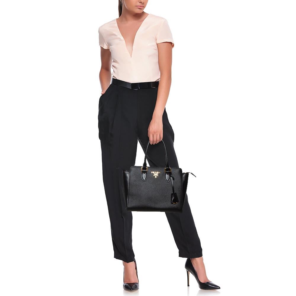 Feminine in shape and grand on design, this tote by Prada will be a loved addition to your closet. It has been crafted from Saffiano Lux leather and styled minimally with gold-tone hardware. It comes with two top handles and a perfectly-sized