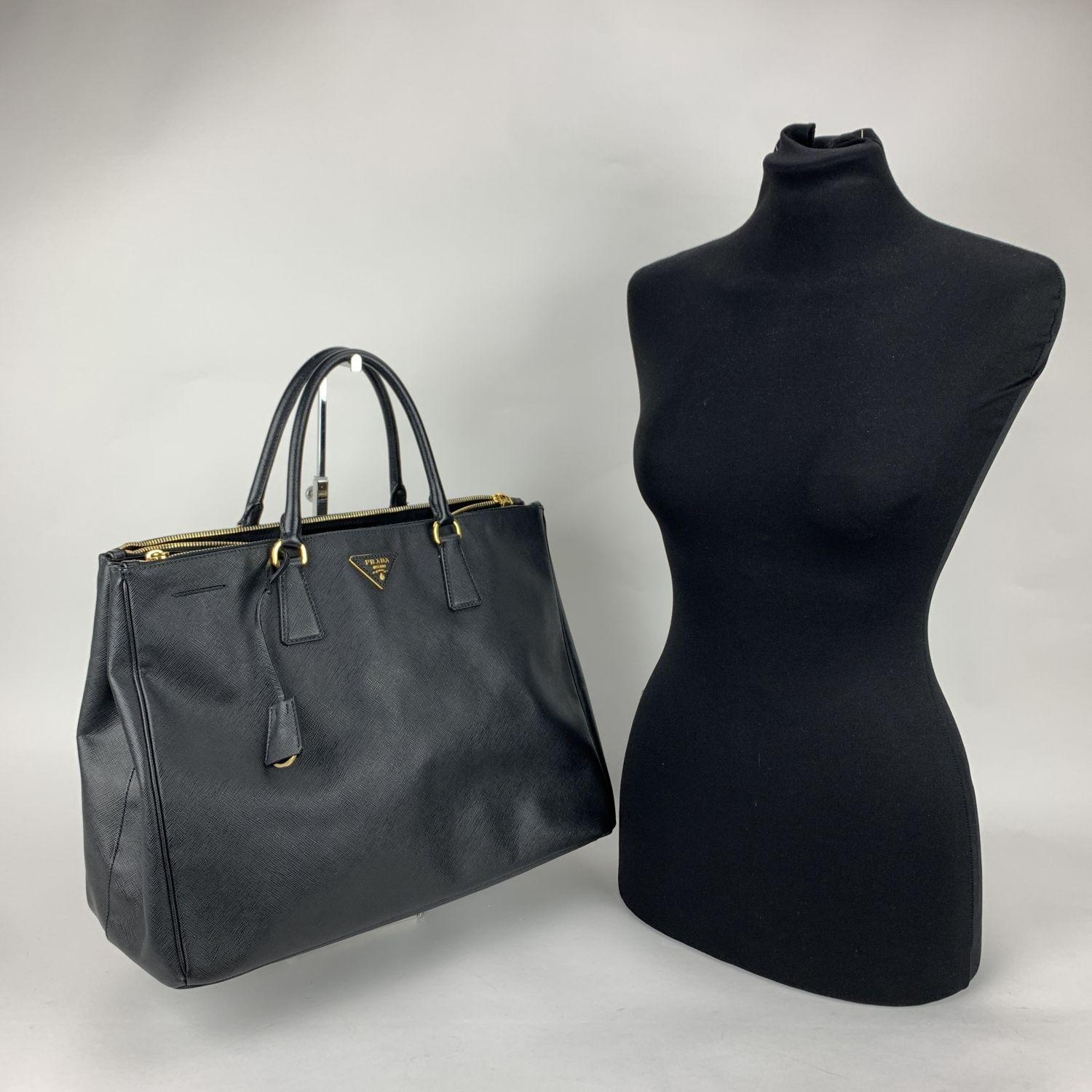 Stunning PRADA top handles bag/handbag mod. BN1802, designed in black Saffiano Lux leather and finished with leather triangle logo on the front, all in a structured tote silhouette. It features a removable keychain with leather clochette, double