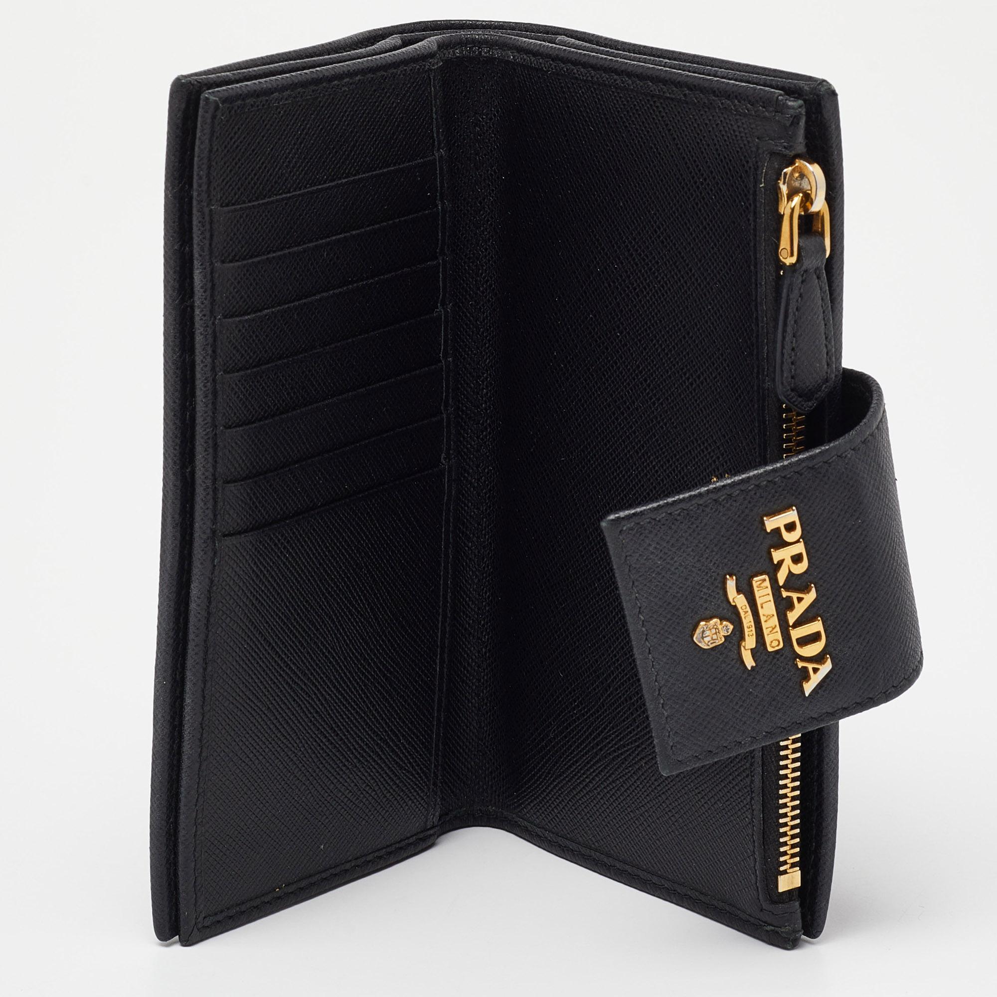 Made of elegant Saffiano leather in stark black, this continental wallet from Prada is a classy choice. The flap with a snap button opens to multiple card slots and a zipped pocket. This wallet is complete with a gold-tone logo on the flap.