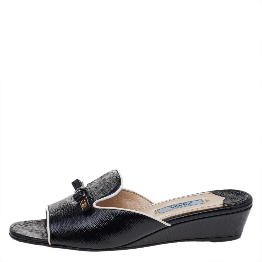 Minimal design and optimal comfort are the special features of these Prada sandals. They come crafted from Saffiano patent leather and feature an open-toe silhouette. They are styled with wide vamp straps that flaunt gold-tone brand logo details and