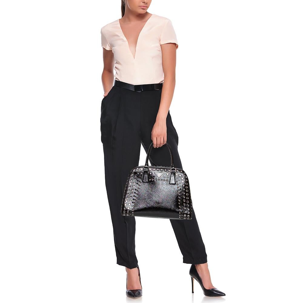 Giving handle bags an elegant update, this Pyramid Frame bag by Prada will be a valuable addition to your closet. It has been crafted from patent leather and styled with stud embellishments. It comes with dual top handles, protective metal feet at