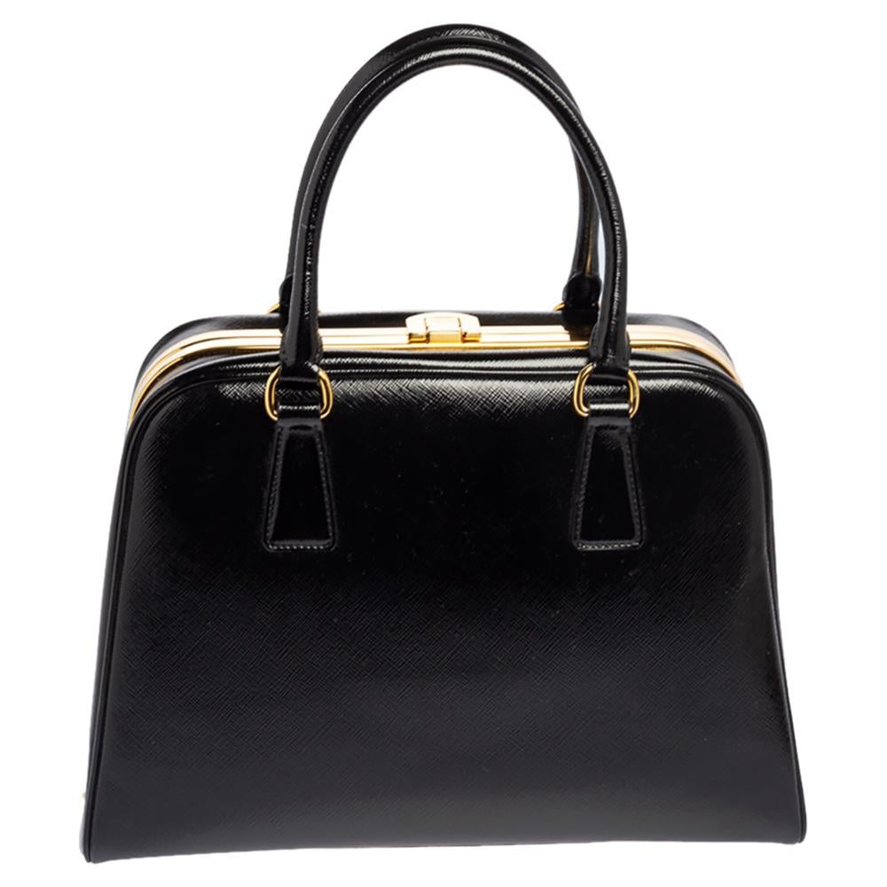 Giving handle bags an elegant update, this Pyramid Frame bag by Prada will be a valuable addition to your closet. It has been crafted from Saffiano Vernice leather and styled with gold-toned hardware. It comes with dual top handles, protective metal