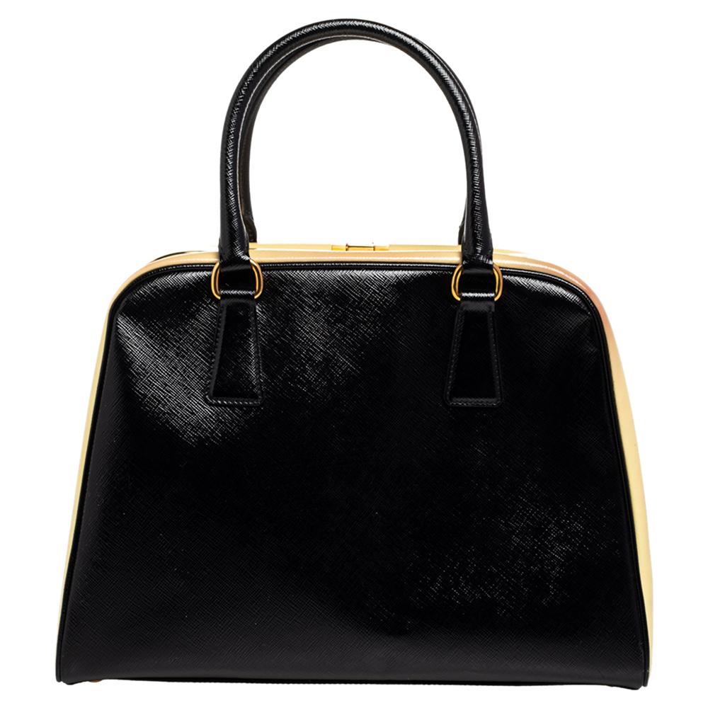 Giving handle bags an elegant update, this Pyramid Frame bag by Prada will be a valuable addition to your closet. It has been crafted from Saffiano Vernice leather and styled with gold-toned hardware. It comes with dual top handles, protective metal