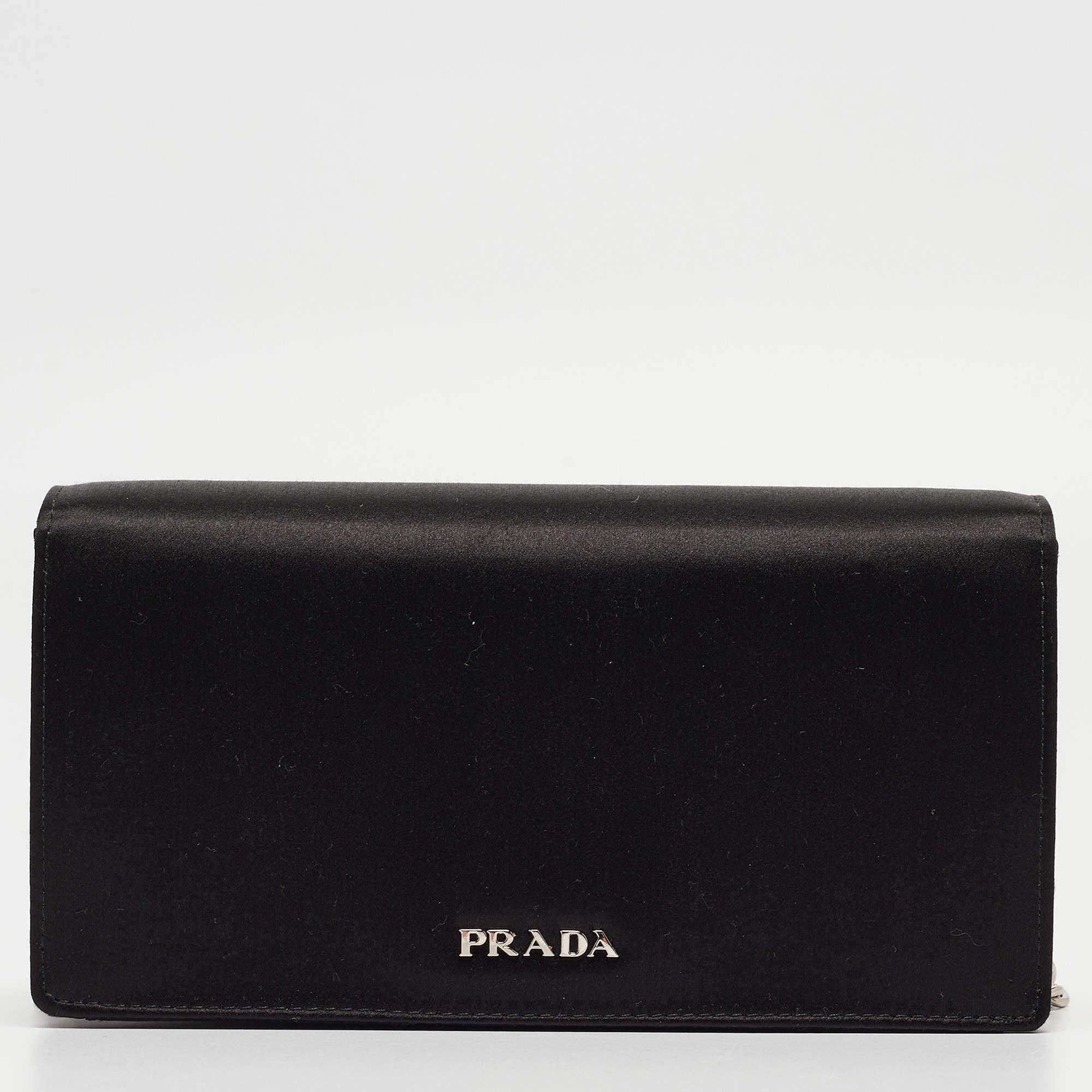 This clutch by Prada will make sure you are equipped to impress when you step out for all your evening events. This bag is crafted from black satin and styled with a front flap embellished with crystals. It has a spacious satin interior, silver-tone