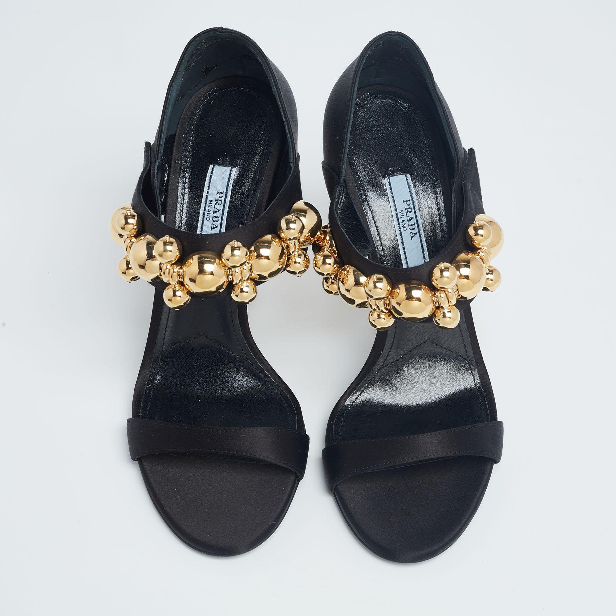 Inspired by the vintage Mary Jane style, these sandals from the House of Prada are going to be your favorite. They are designed luxuriously using black satin, which is enhanced with gold-tone embellishments. They feature open toes and 12 cm heels.