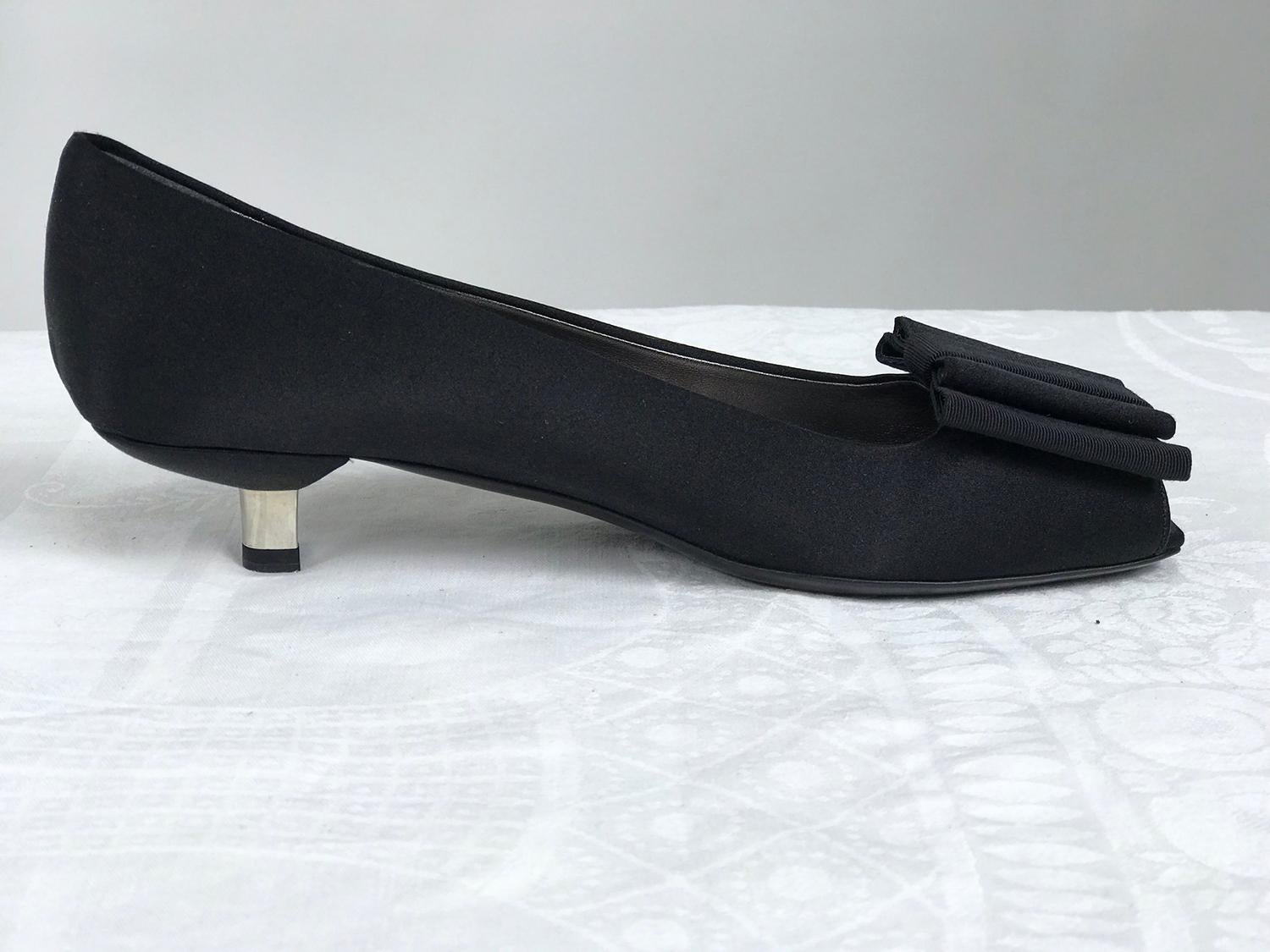 Prada black satin open toe bow front, low silver metal heel pump, 37. 1 1/4 inch heel. These amazing shoes have never been worn. The front has a large gros grain and satin bow with an open toe. The heel is low and shaped the upper is satin with a
