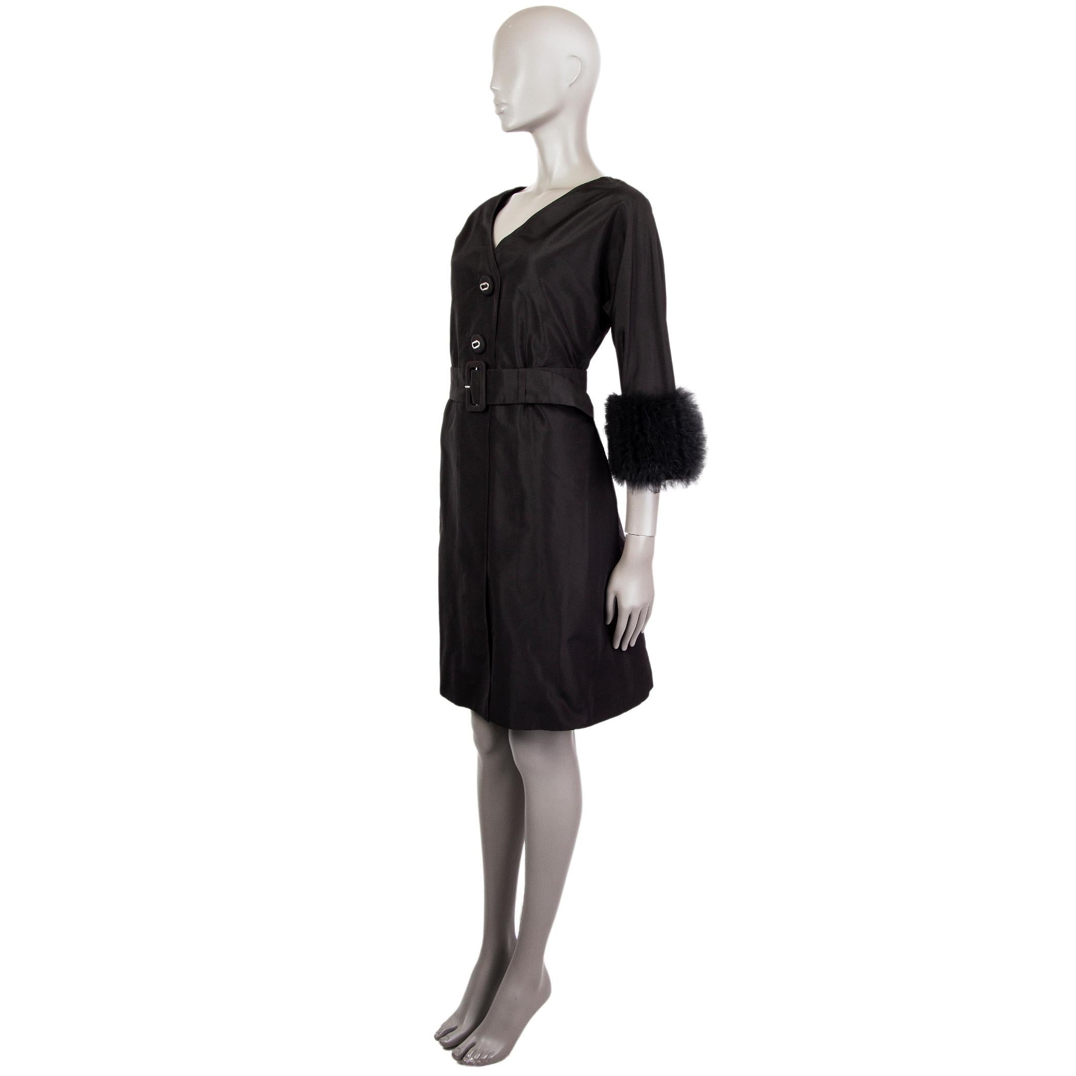 Prada shift dress in black silk (100%). With v back, ruffled tulle cuffs in black nylon (100%), and two slit pockets on the sides. Closes with two large black fabric-lined buttons on the back. Lined in black viscose (67%) and silk (33%).  Comes with