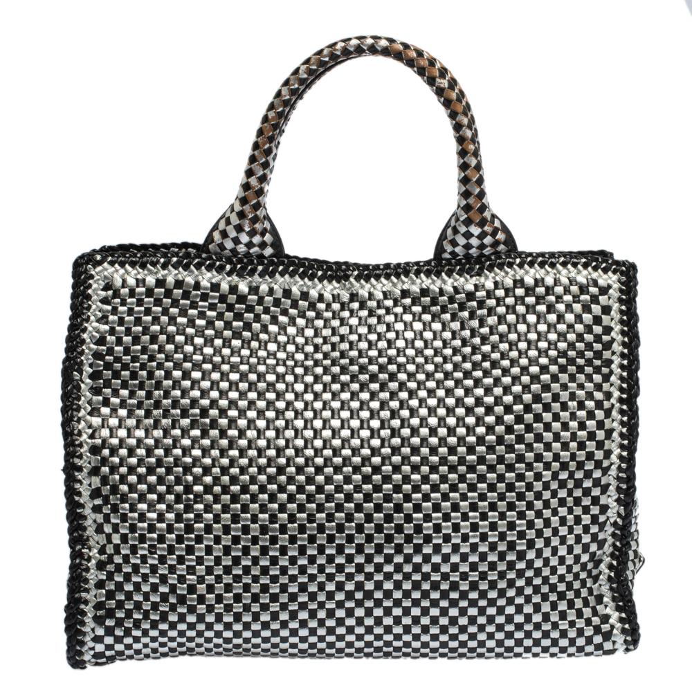 This eye-catching tote from Prada has a timeless charm. The bag is woven from leather in black and silver. It has dual round handles, a detachable shoulder strap and protective metal feet at the bottom. Ideal for everyday use, the bag has enough