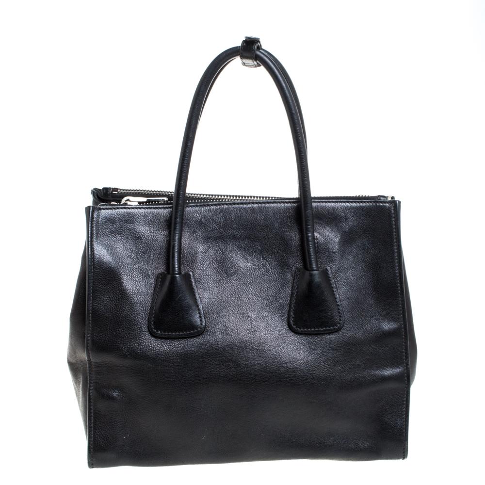 Add some effortless style and luxury to your everyday looks with this stunning Prada tote. Crafted in black leather, this bag can store all that you need through the day or for work in its large middle compartment and two zippered compartments. The