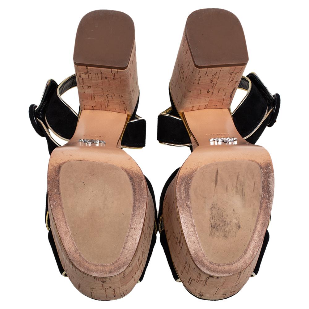 When comfort is of utmost priority, opt for these sandals from Prada. This pair comes with black suede straps enhanced with gold piping, ankle strap closure, and chunky cork heels set on matching platforms. Team them with everything from dresses to
