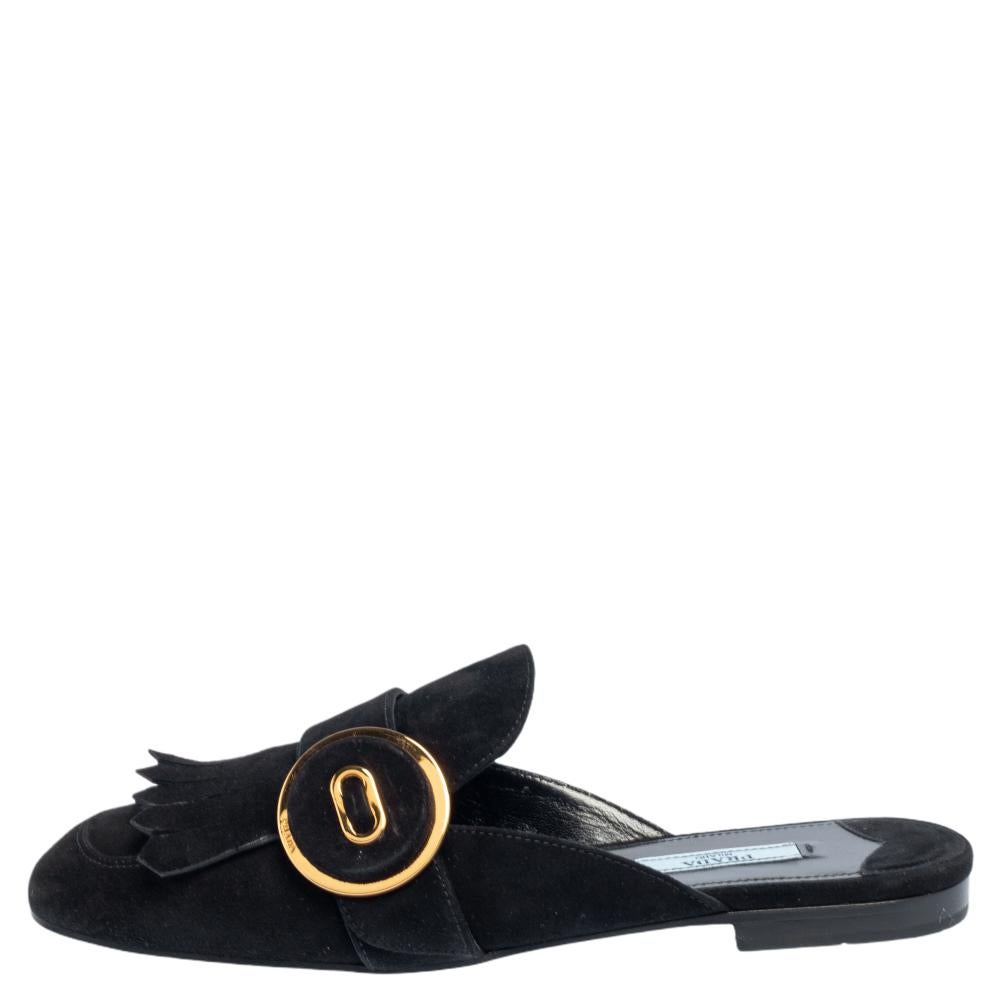 Absolutely on-trend and easy to flaunt, this pair of mules by Prada is a true stunner. The black mules have been crafted from suede and styled with folded fringes and a gold buckle detail on the uppers. Comfortable insoles complete the chic pair to