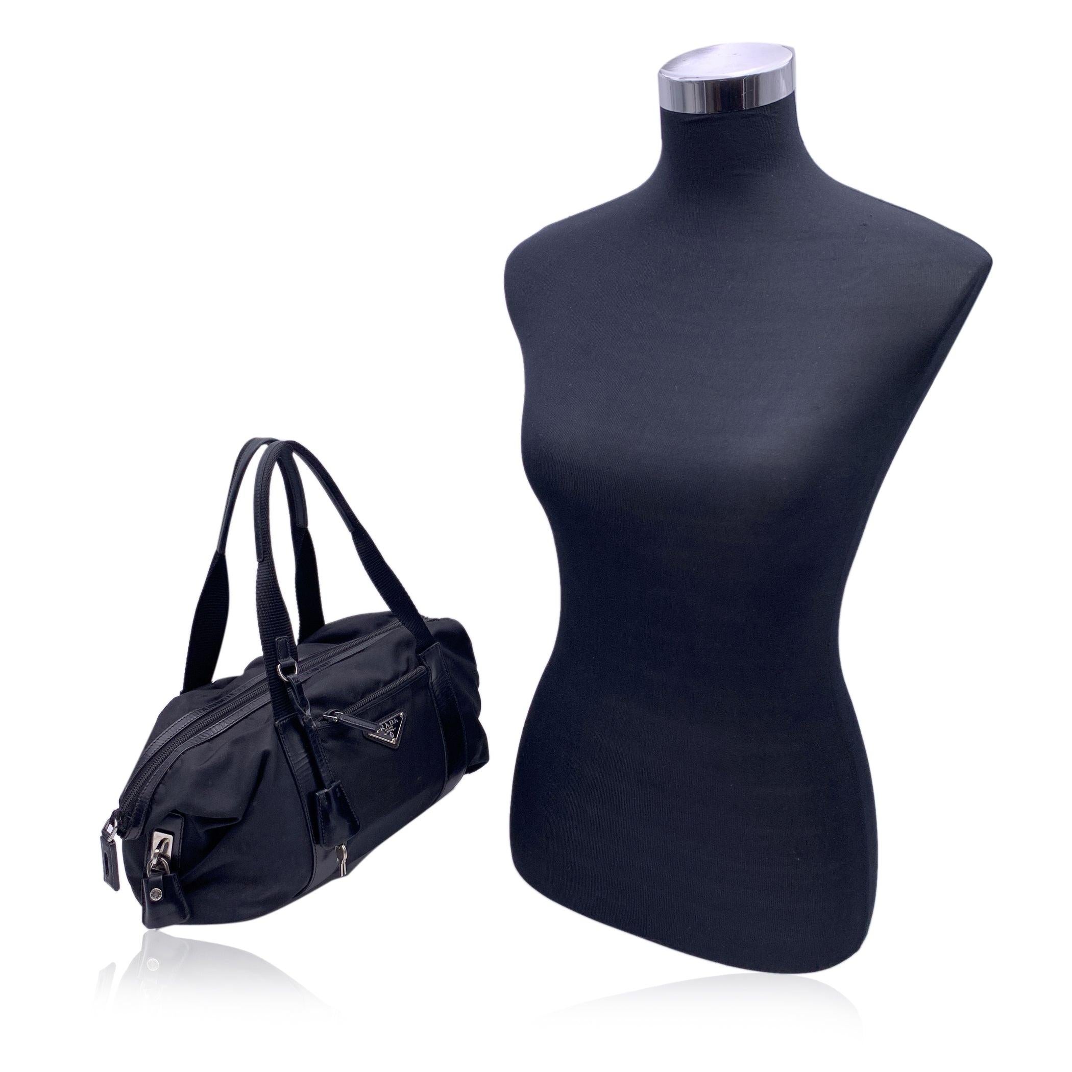 Stunning PRADA tote bag in black nylon and leather. It features upper zipper closure, 1 small front zip pocket. Prada triangle logo on the front. Original Prada padlock and keys included. The bag has 1 main open compartment. The interior is fully