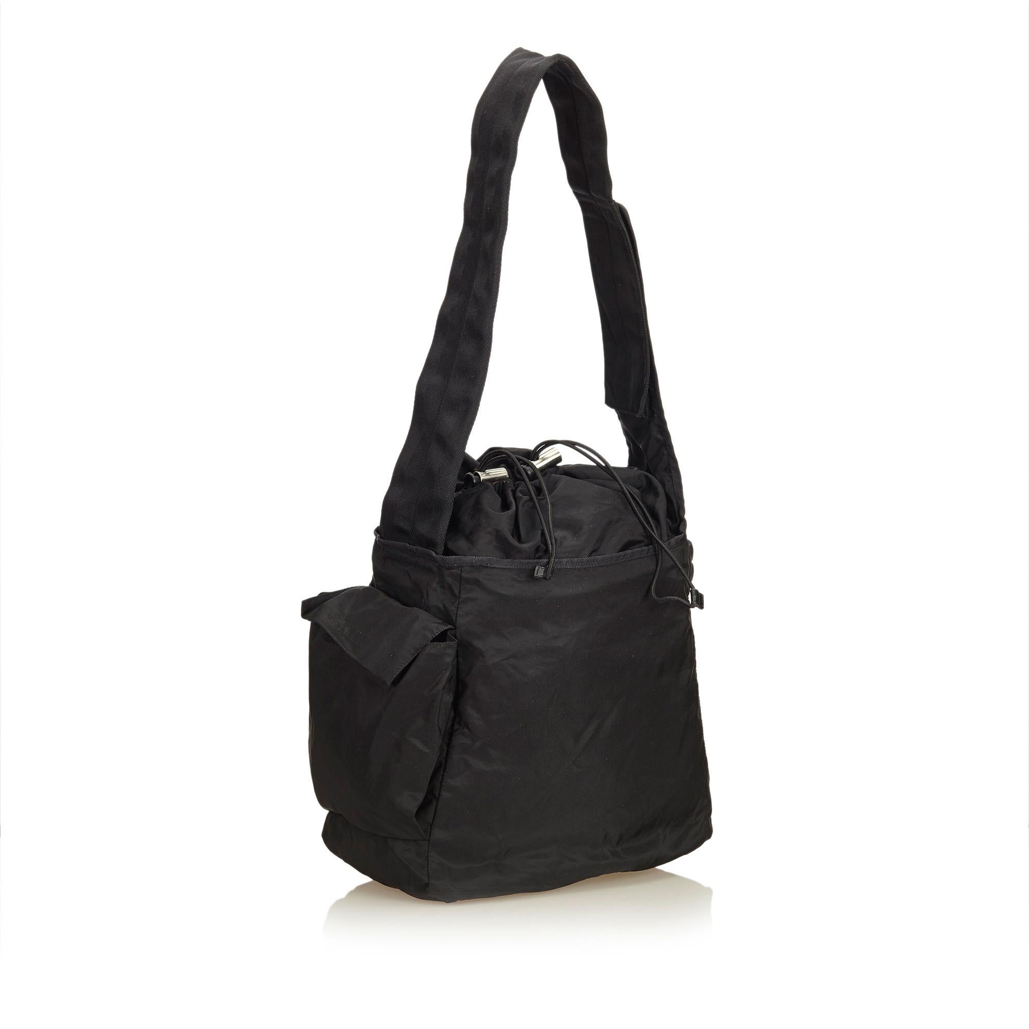 This shoulder bag features a nylon body, flat strap, drawstring closure, exterior flap and slip pockets and interior zip pocket. It carries as B+ condition rating.

Inclusions: 
This item does not come with inclusions.

Dimensions:
Length: 30.00