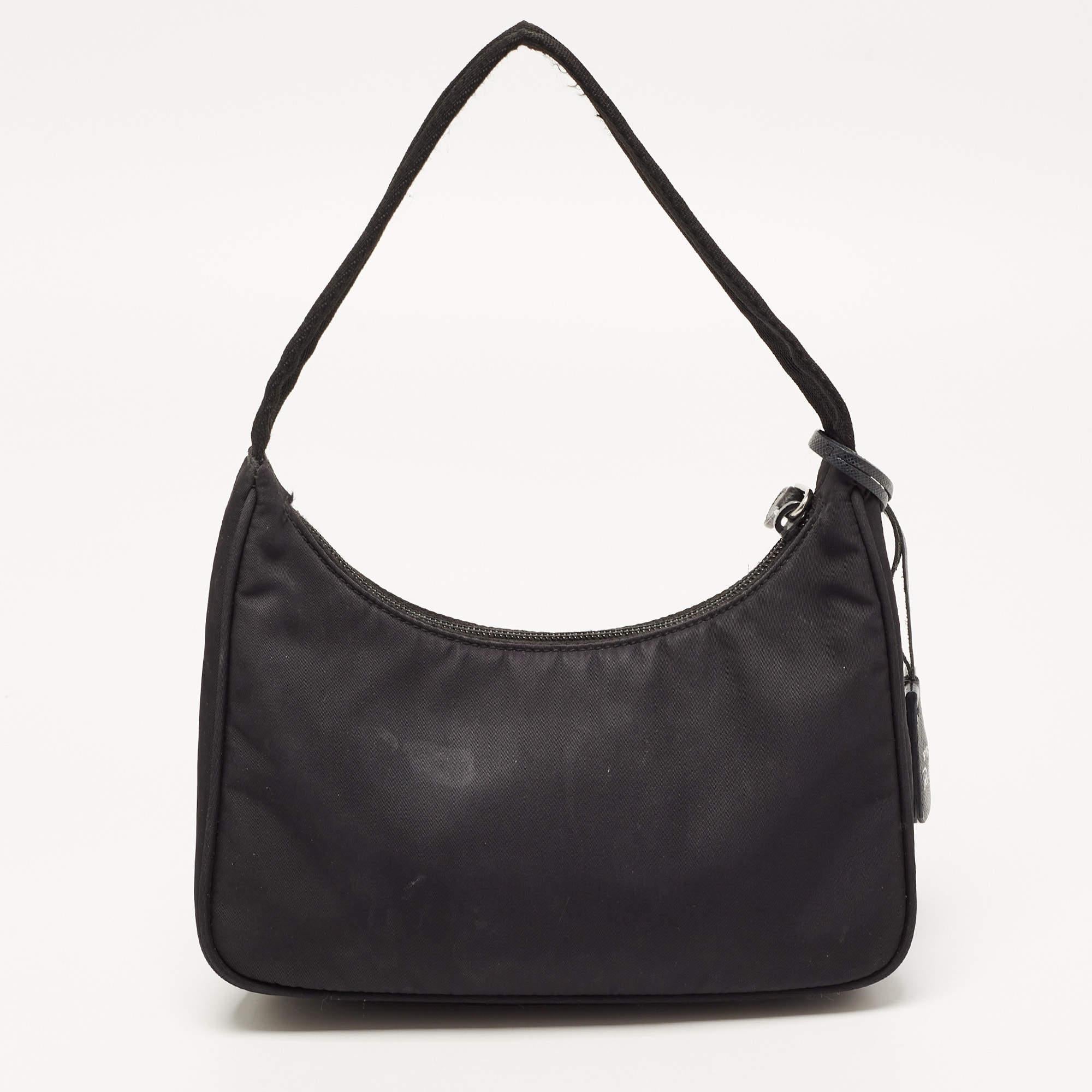 The petite silhouette and classic elements made the Prada Re-Edition 2000 bag an instant hit among fashionistas. With a timeless appeal, this black creation comes made from nylon and features a brand tag attached to the single handle at the top. The
