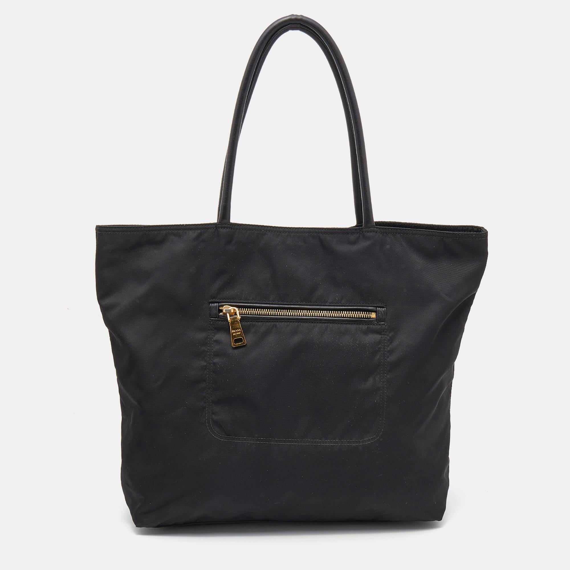 Perfect for work or travel, this Prada tote is made of Tessuto nylon to be classy and durable. It has leather shoulder handles, exterior zip pockets, a brand signature on the front, and a spacious lined interior.

