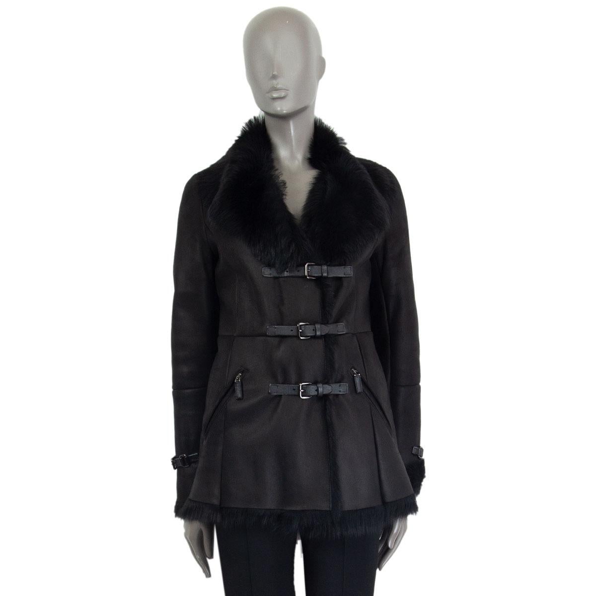 Prada jacket in black shearling and sheep fur with a notch collar, zipper pockets and decorative belted cuffs. Fastens in the front with three leather belts with metal buckles. Has been worn and is in excellent condition. 

Tag Size 40 
Size
