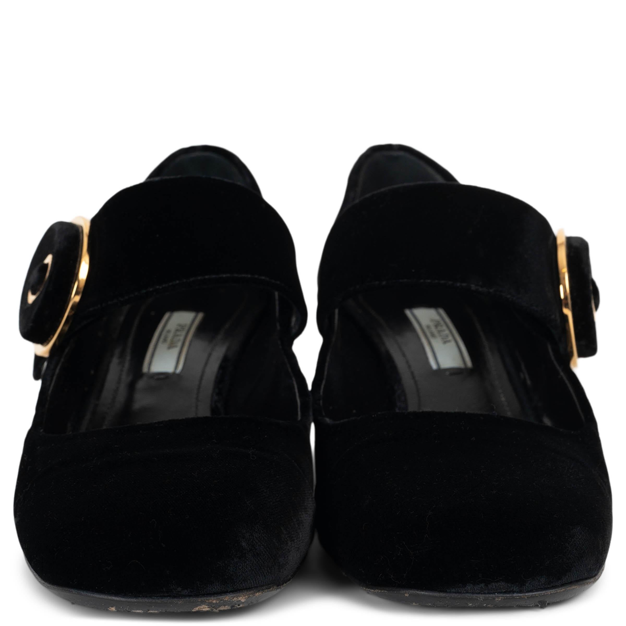 Este par de zapatos de salón Prada Mary-Jane 100% auténticos están confeccionados en lujoso terciopelo negro y llevan un elegante cierre redondo dorado que les da un toque refinado. Sobre un cómodo tacón en bloque, estos zapatos de salón combinan