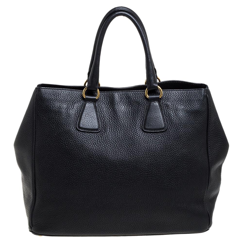Complete your look with this impeccably crafted tote from Prada. The Vitello Daino made tote features double top handles and gold-tone hardware. The bag opens to a spacious nylon-lined interior for you to store your essentials. This bag is great for