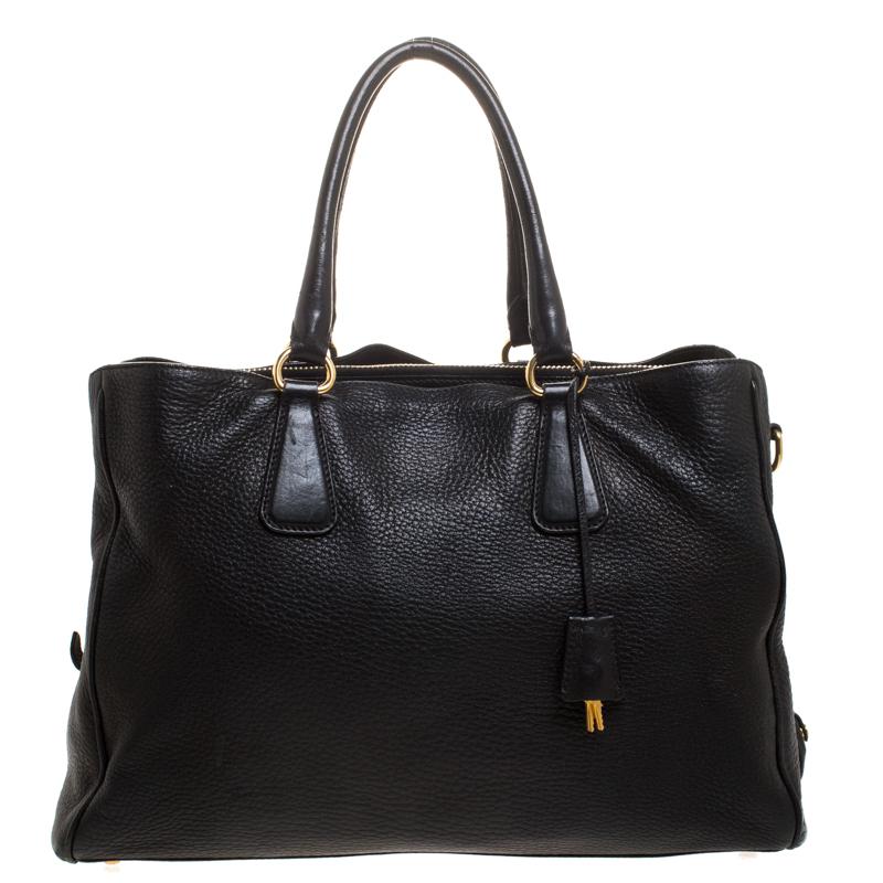 Complete your look with this impeccably crafted tote from Prada. The Vitello Daino tote features double top handles, a detachable shoulder strap that can be adjusted to the desired length and gold-tone hardware. The bag opens to a nylon-lined