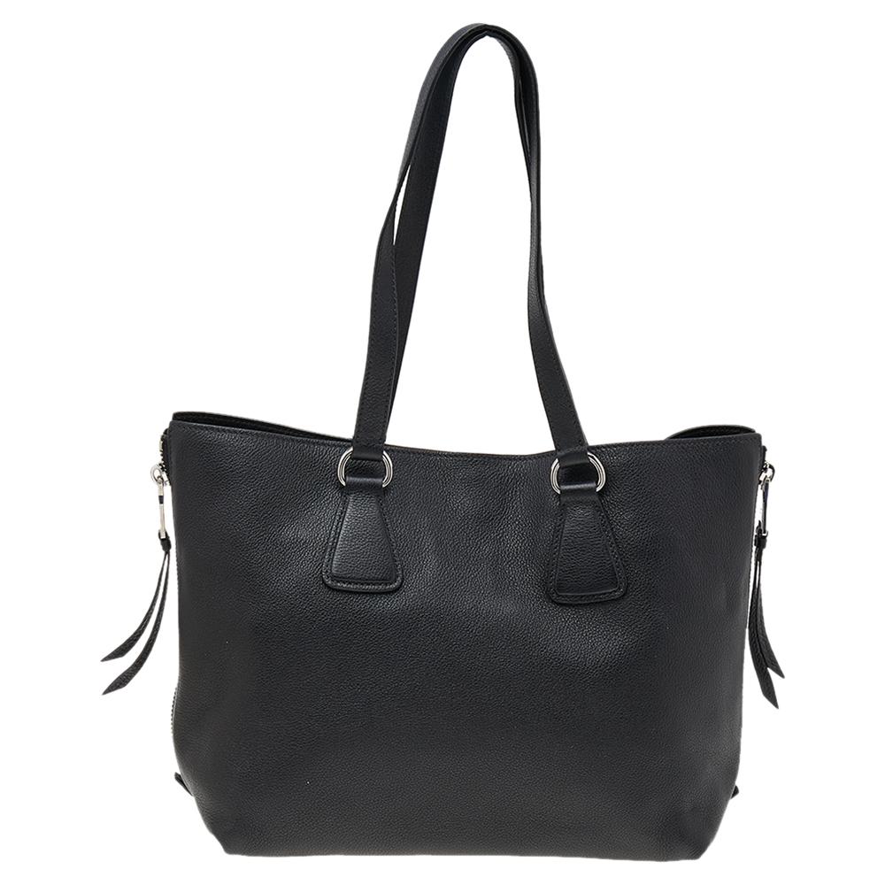 Prada brings you this tote that is overflowing with style. Covered in black, the bag brings a spacious nylon interior to dutifully hold all your necessities and side zippers that can be unzipped to accommodate more things. Leather-made, the bag is