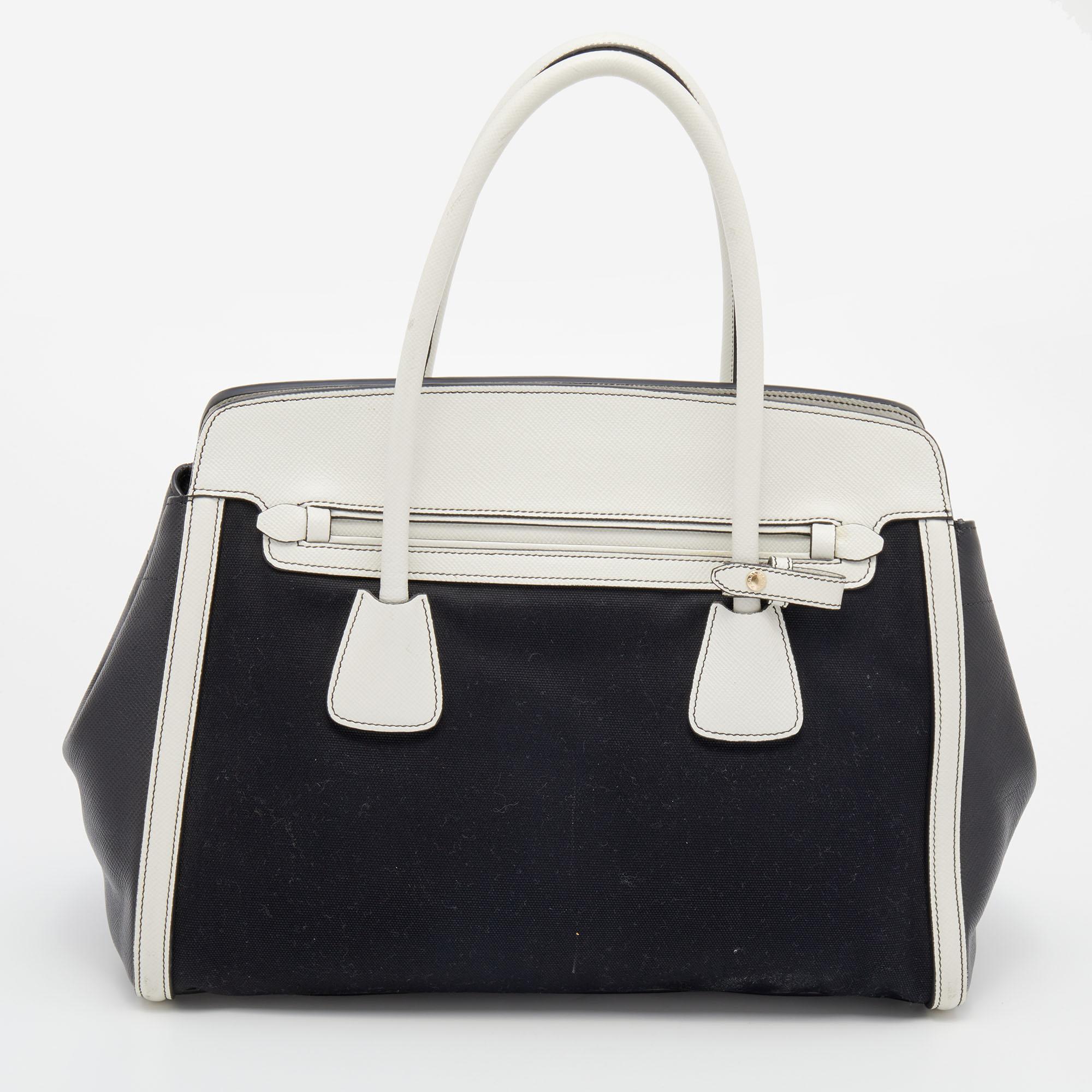 Prada showcases a masterfully designed tote for you to carry everywhere. Complemented with a black and white color combination, this fashionable bag is all you need in your closet. It has been crafted from canvas and leather into a structured shape