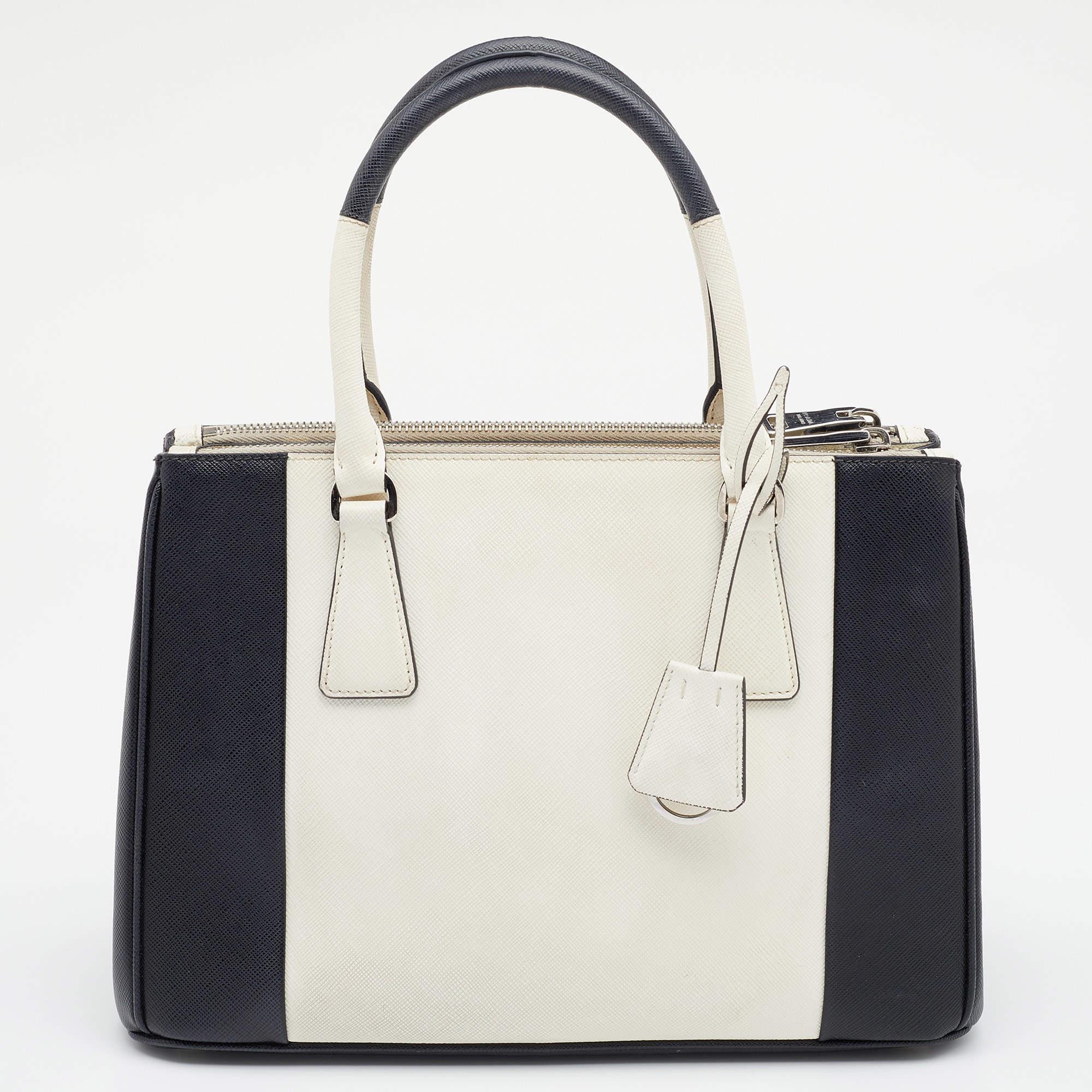 This Double Zip tote by Prada will be a loved addition to your closet. It has been crafted from Saffiano Lux leather and styled with gold-tone hardware and dual shades. It comes with two top handles, two zip compartments, and a perfectly-sized main