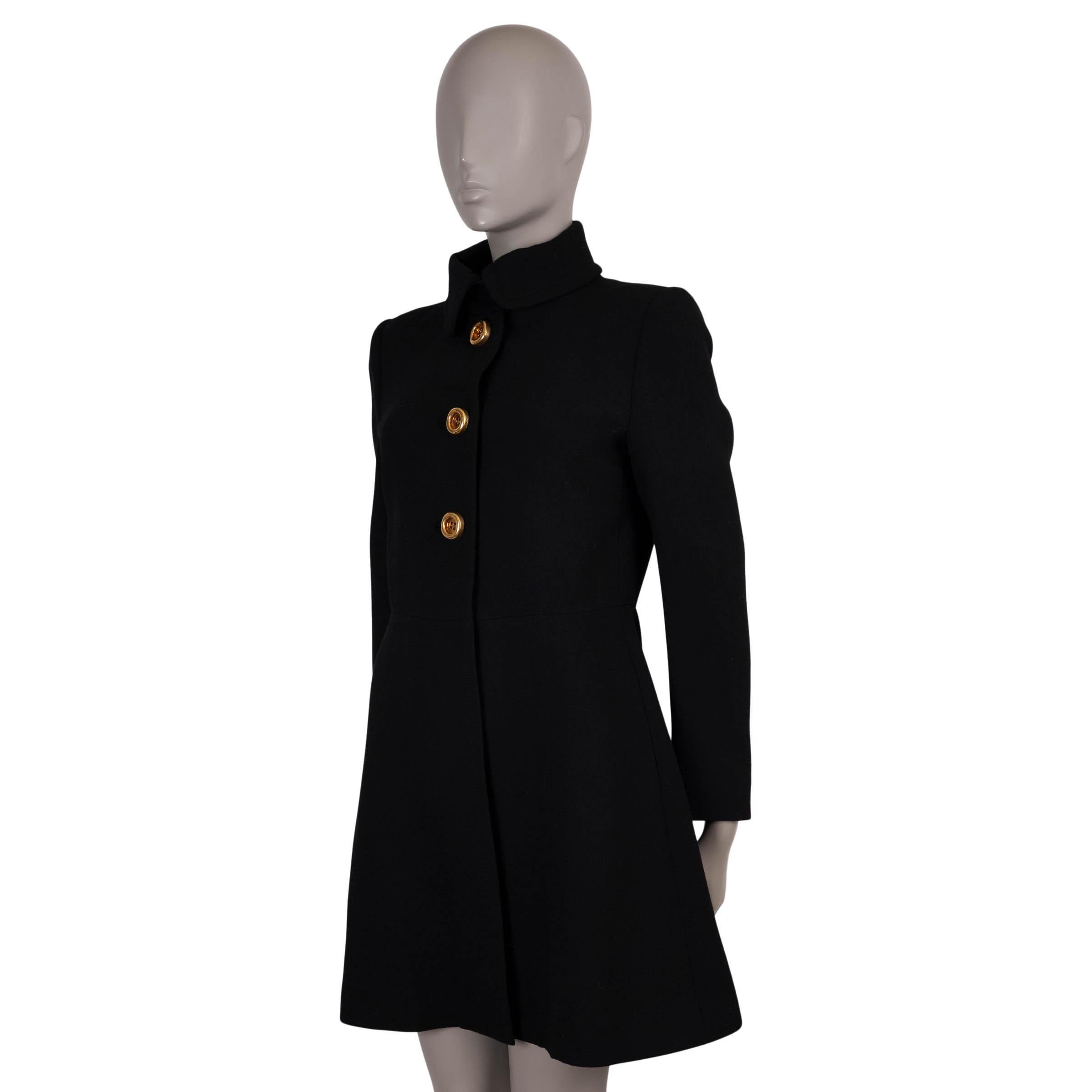 Questo cappotto 100% autentico di Prada è realizzato in lana nera (100%). Presenta una classica silhouette aderente con maniche lunghe, due tasche a fessura e tre bottoni decorativi dorati. Il cappotto si chiude con bottoni a pressione nascosti sul