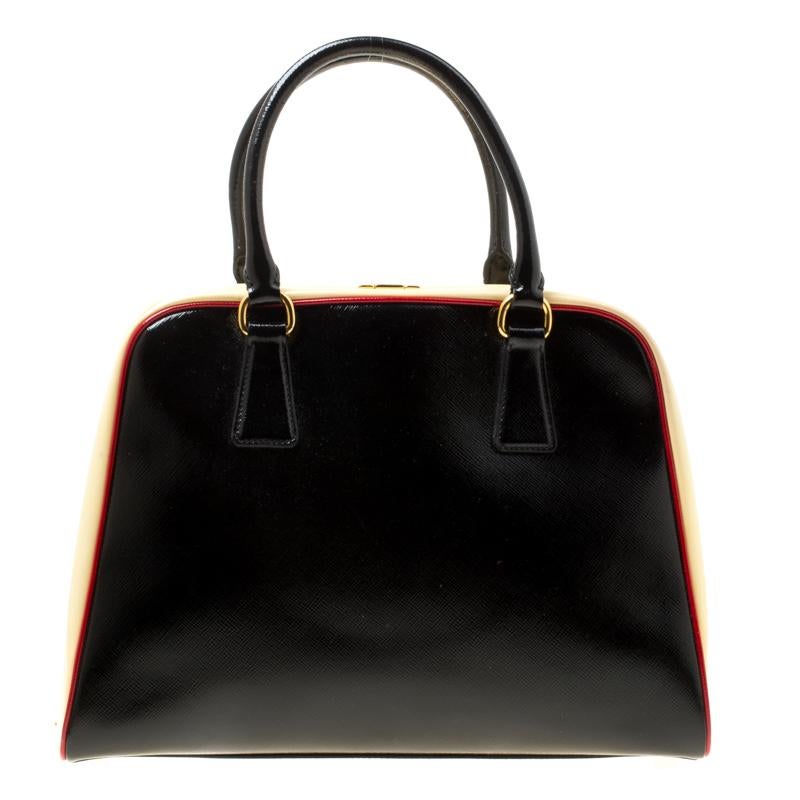 Giving handle bags an elegant update, this Pyramid Frame bag by Prada will be a valuable addition to your closet. It has been crafted from patent leather and it comes with dual top handles, protective metal feet at the bottom and a perfectly sized