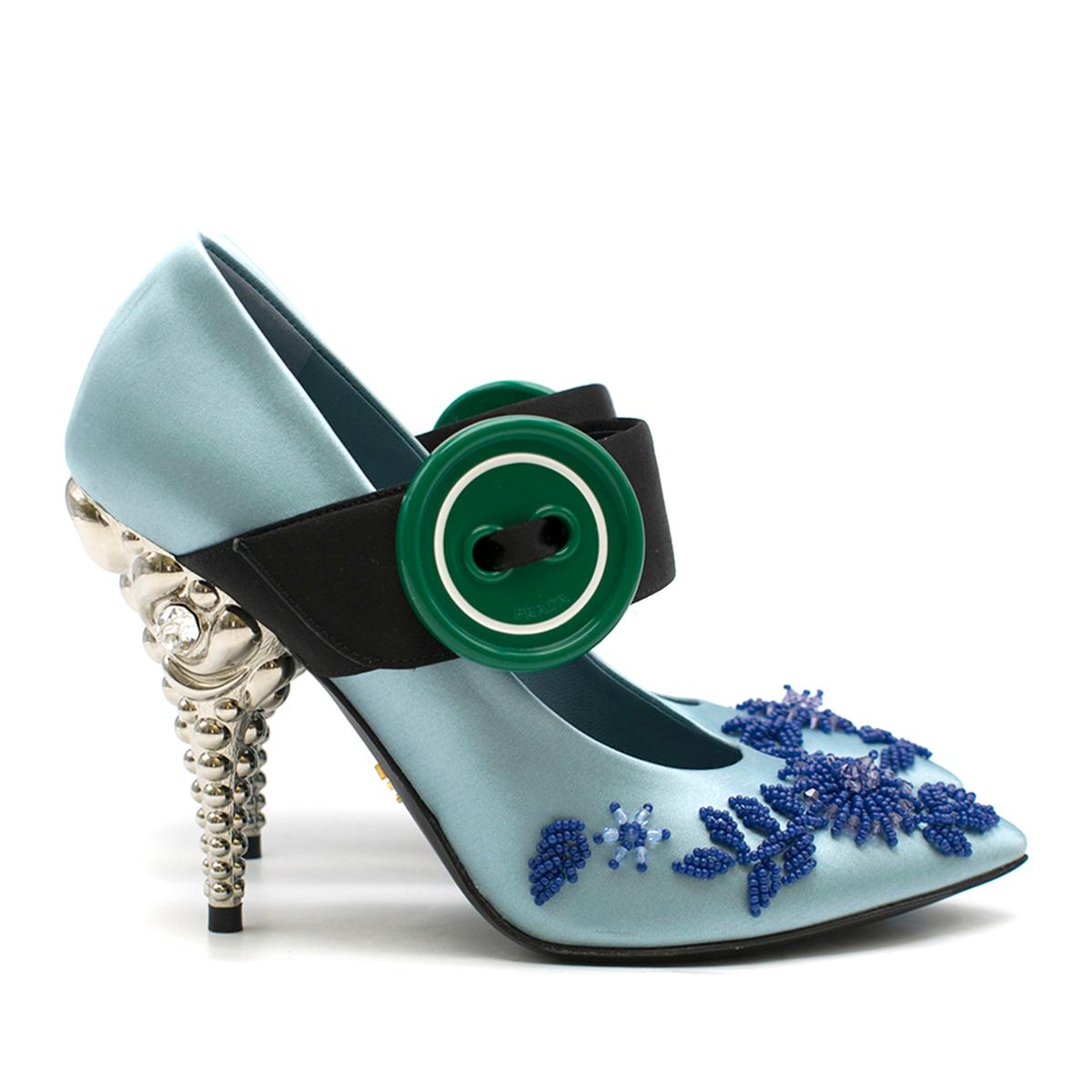 Prada Blue Bead-embellished Satin Pump

- Blue satin pump
- Pointed toe
- Front bead embellishment 
- Front black strap with oversized green button
- Silver-tone 3-D decorative high heel, clear crystal embellished 
- Blue leather lining with logo