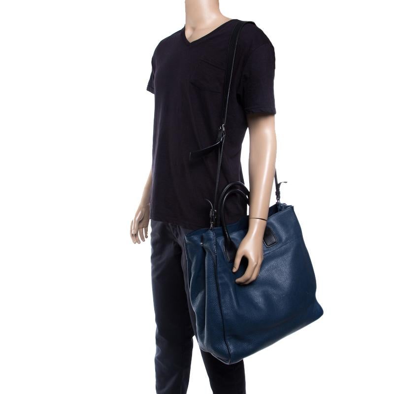 Elegantly crafted exuding a classic finish, this Prada tote is a must-have bag in any fashionista's collection. Made of blue-colored leather and decorated with black trims, it features a long shoulder strap along with two flat top handles that sit