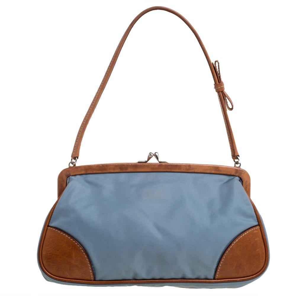 This stylish pochette bag by Prada is great for parties. Crafted from blue & brown nylon & leather, it has a frame that adds interest. The strap closure carries the brand logo. It has a nylon interior, a single handle, and silver-tone hardware